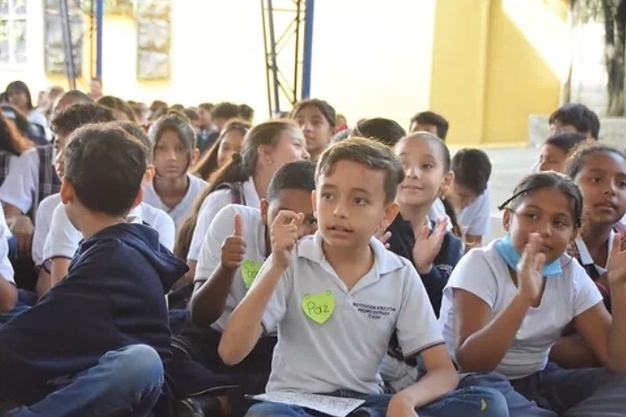 Foto de niños sentados en la cancha de una escuela