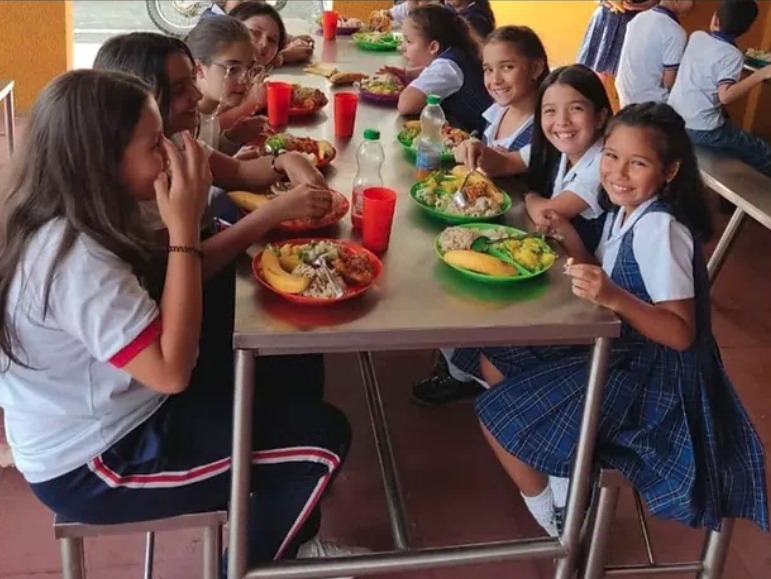 Foto de niñas comiendo en una mesa en el restaurante escolar